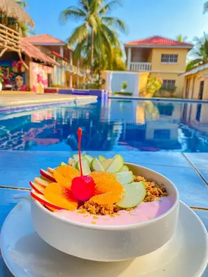 a bowl of fruit on a plate next to a pool at Hotel y Restaurante Punta Diamantes in Acajutla