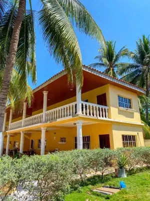 a yellow house with palm trees in front of it at Hotel y Restaurante Punta Diamantes in Acajutla