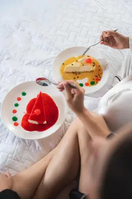 a woman sitting on a bed with two plates of food at Hotel y Restaurante Punta Diamantes in Acajutla