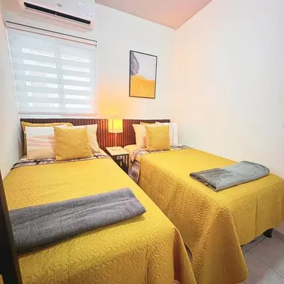two beds in a room with yellow sheets at Casa Málaga en San Miguel, El Salvador in San Miguel