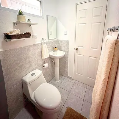 a bathroom with a white toilet and a sink at Casa Málaga en San Miguel, El Salvador in San Miguel