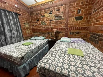 two beds in a room with a brick wall at San Fernando in Concepción de Ataco