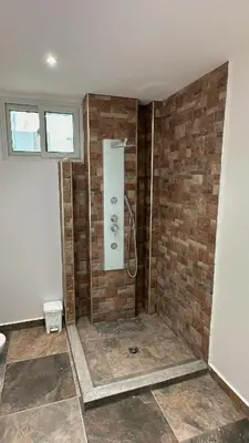 a bathroom with a shower with a brick wall at Mariposa Reina A in El Tamarindo