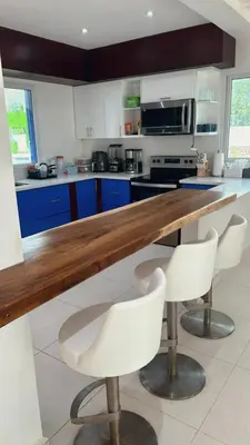 a kitchen with a wooden counter and white chairs at Mariposa Reina A in El Tamarindo