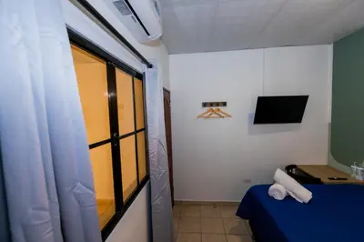 a small room with a blue bed and a television at Friendly House in Nueva San Salvador