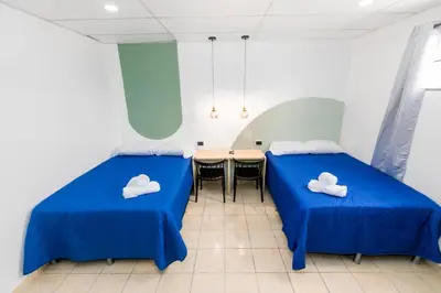 a room with two beds and a table and chairs at Friendly House in Nueva San Salvador