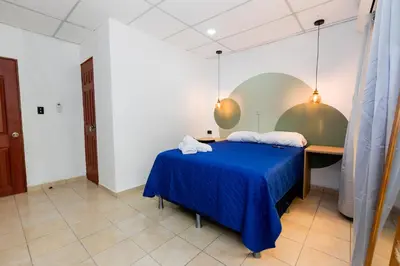 a bedroom with a blue bed and a desk at Friendly House in Nueva San Salvador