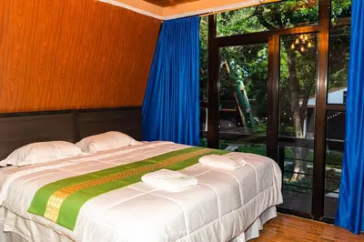a bedroom with a bed with blue curtains and a window at Hacienda Rubí Club & Resort in San Miguel