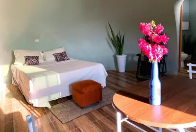 a bedroom with a bed and a vase of flowers on a table at Las Terrazas de el Alto in Chalatenango