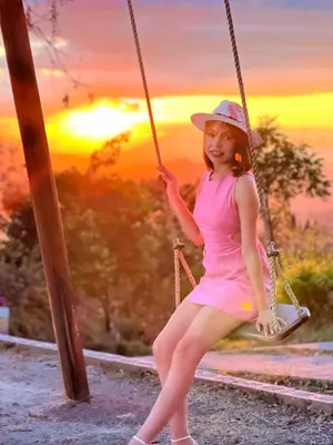 a young girl sitting on a swing at sunset at Las Terrazas de el Alto in Chalatenango