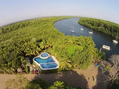 an island with a boat in the middle of a river at Puerto Barillas in Bahia de Jiquilisco