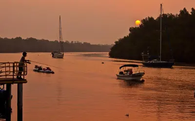 a group of people in boats on a river at sunset at Puerto Barillas in Bahia de Jiquilisco
