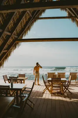 a man standing on the beach looking out at the ocean at Almare Zonte - BeachFront Glamping Hotel in El Zonte