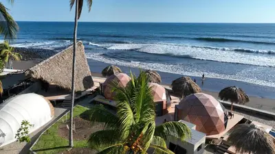 a view of a beach with domes and the ocean at Almare Zonte - BeachFront Glamping Hotel in El Zonte