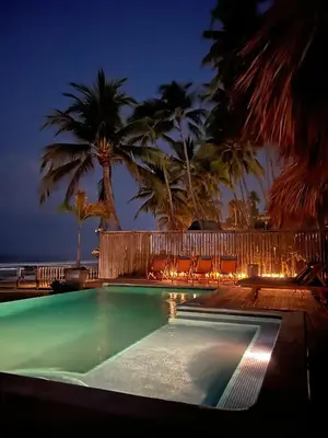a swimming pool at night with palm trees at Almare Zonte - BeachFront Glamping Hotel in El Zonte