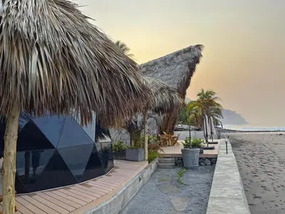 a resort on the beach with chairs and palm trees at Almare Zonte - BeachFront Glamping Hotel in El Zonte