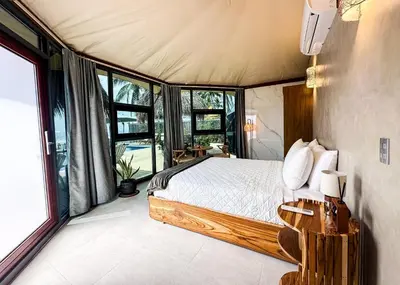 a bedroom with a bed in a room with windows at Almare Zonte - BeachFront Glamping Hotel in El Zonte