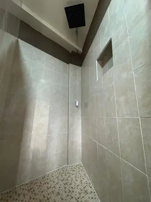 a bathroom with a shower with a tiled wall at Tiny Room El Mangal B&B in Suchitoto