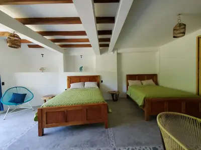 a bedroom with two beds and a blue chair at Wayo loft en Playa El Tunco Surf City in Tamanique