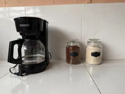 a coffee maker and two jars on a counter at Hostal Tia Reyna in El Zonte