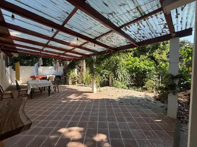 a patio with a wooden pergola and a table at Hostal Tia Reyna in El Zonte
