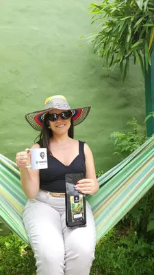 a woman sitting on a hammock holding a cell phone at D Origen House APANECA in Apaneca