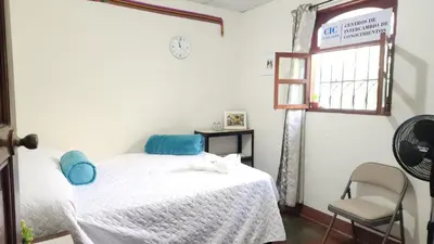 a bedroom with a bed and a window and a chair at D Origen House APANECA in Apaneca