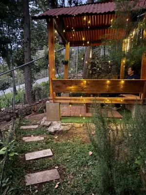 a man sitting on a wooden bench in a garden at Cabaña privada en Los Naranjos in Los Naranjos