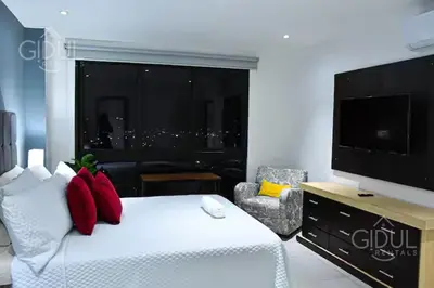 a hotel room with a bed and a flat screen tv at Modern apt with stunning city and mountain views in San Salvador