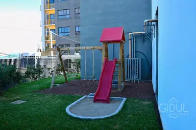 a playground with a red slide in a yard at Modern apt with stunning city and mountain views in San Salvador