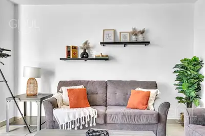 a living room with a gray couch and orange pillows at Modern apt with stunning city and mountain views in San Salvador