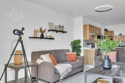 a living room with a gray couch and a kitchen at Modern apt with stunning city and mountain views in San Salvador