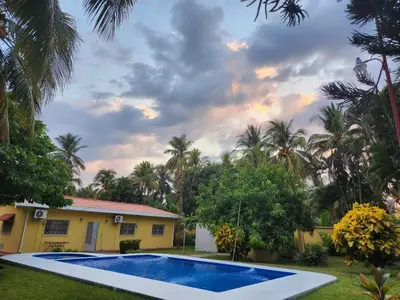 a villa with a swimming pool in front of a house at El Paraíso Escondido in San Luis