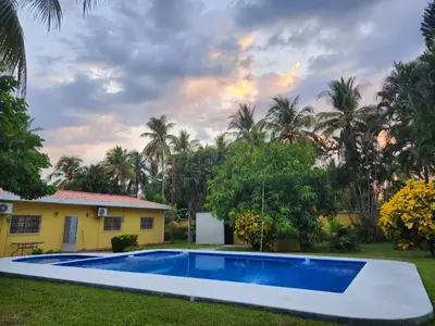 a pool in front of a house with palm trees at El Paraíso Escondido in San Luis