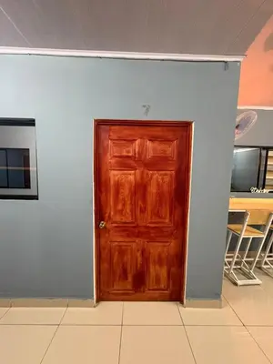 a wooden door in a room with a white wall at Hostal Sunset Town in Ahuachapán