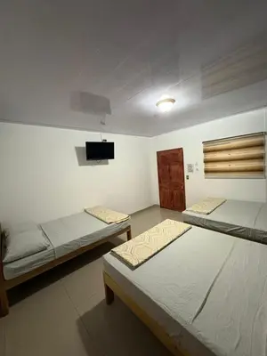 a room with two beds and a tv on the wall at Hostal Sunset Town in Ahuachapán