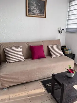 a brown couch with two pink pillows in a living room at Toto's House, near Mall Las Ramblas in Santa Ana