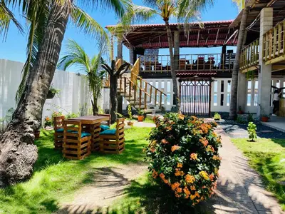 a patio with a table and flowers and palm trees at The Beach Break Hotel El Cocal in Playa San Blas