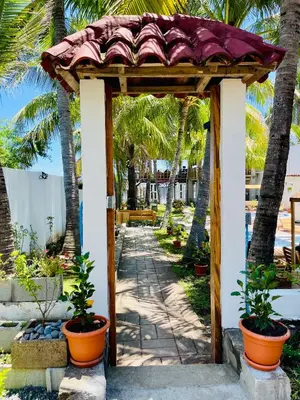 a pergola with palm trees and a walkway at The Beach Break Hotel El Cocal in Playa San Blas