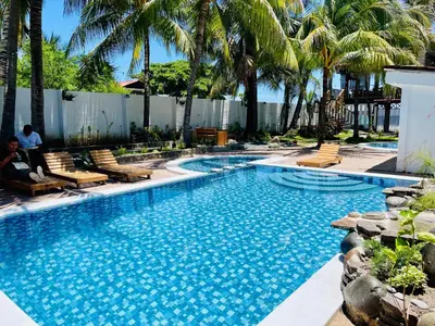 a swimming pool with chairs and palm trees at The Beach Break Hotel El Cocal in Playa San Blas