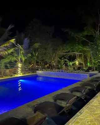 a swimming pool at night with chairs around it at Casa Ruta Termal - Ahuachapan in Ahuachapán