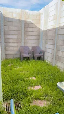 a patio with two chairs and a table in the grass at Tu Hogar Encantado Casa Entera con dos Habitaciones in San Miguel