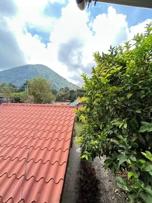 a red roof on a house with a mountain in the background at 1961 Los Naranjos Hostal in Los Naranjos
