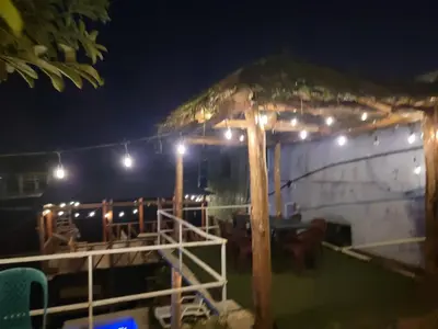a shack with a straw umbrella and chairs at night at Restaurante y Hostal Romayor in Hacienda Santa Rosa