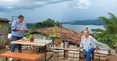 a woman sitting on a bench next to a table at CASA LICHIs in Suchitoto