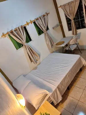 a bedroom with a bed and a table and windows at Casa de Limón 01 in Santa Ana