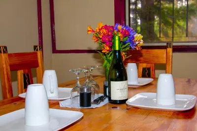 a bottle of wine and a vase of flowers on a table at Lacasadelbosquesv in Río Chiquito
