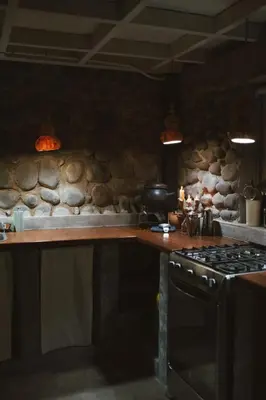 a kitchen with a stove and a stone wall at Unique Tiny House-Best Beach in El Zonte in El Zonte
