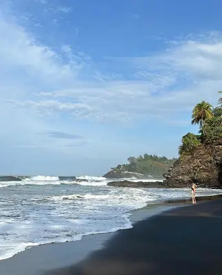 a person standing on a beach near the ocean at Unique Tiny House-Best Beach in El Zonte in El Zonte