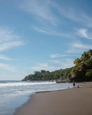 a person standing on a beach next to the ocean at Unique Tiny House-Best Beach in El Zonte in El Zonte